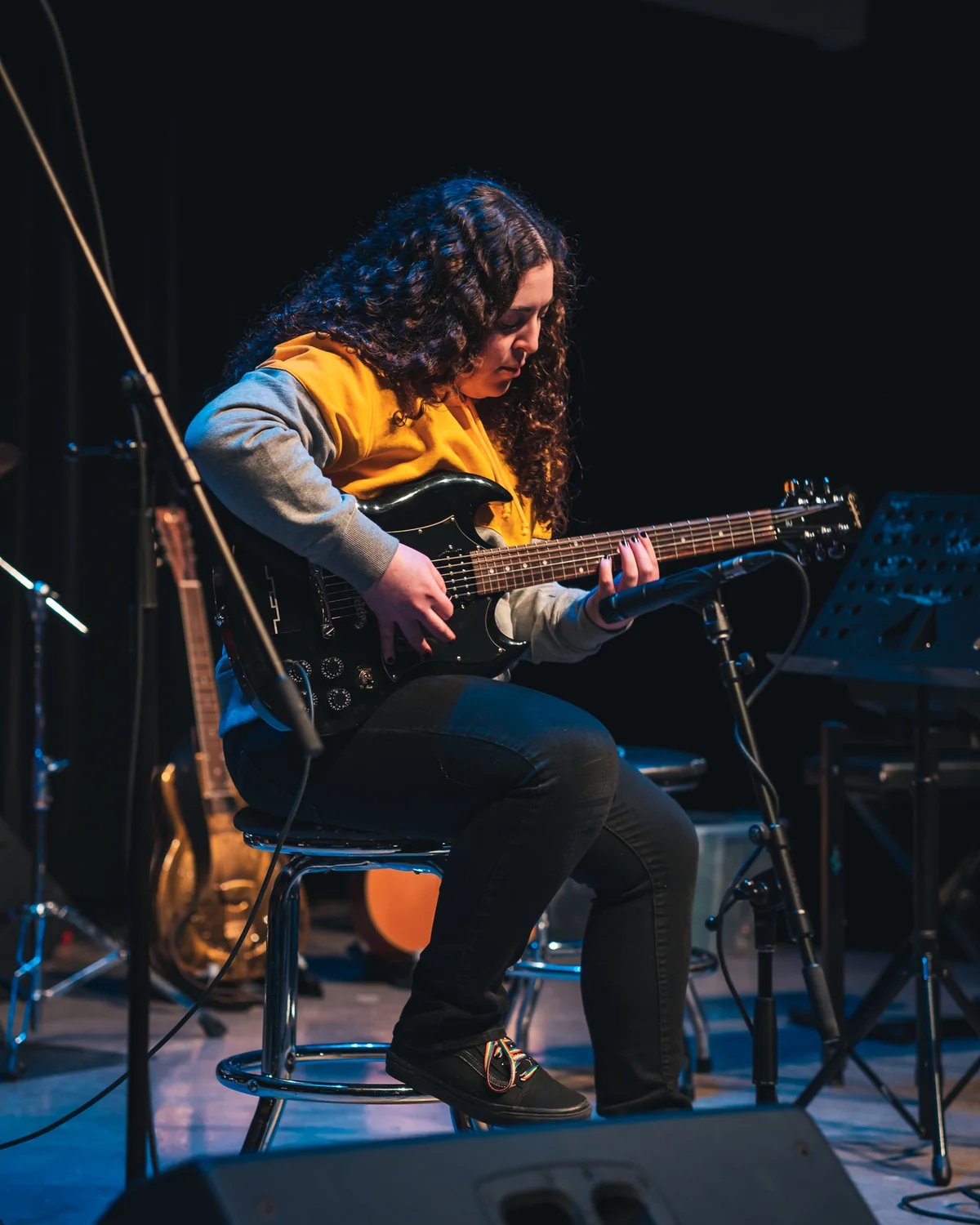 Student focused on playing electric guitar during a recital at Resonate