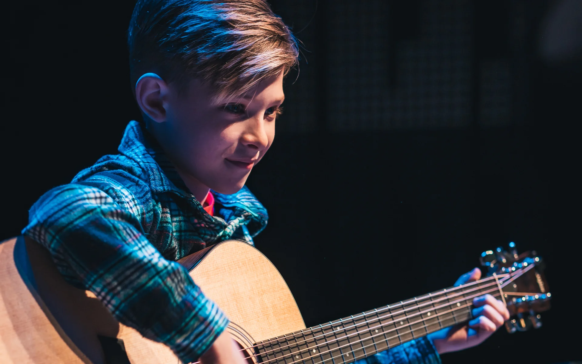 Young student performing on acoustic guitar on stage at Resonate in Edmonton