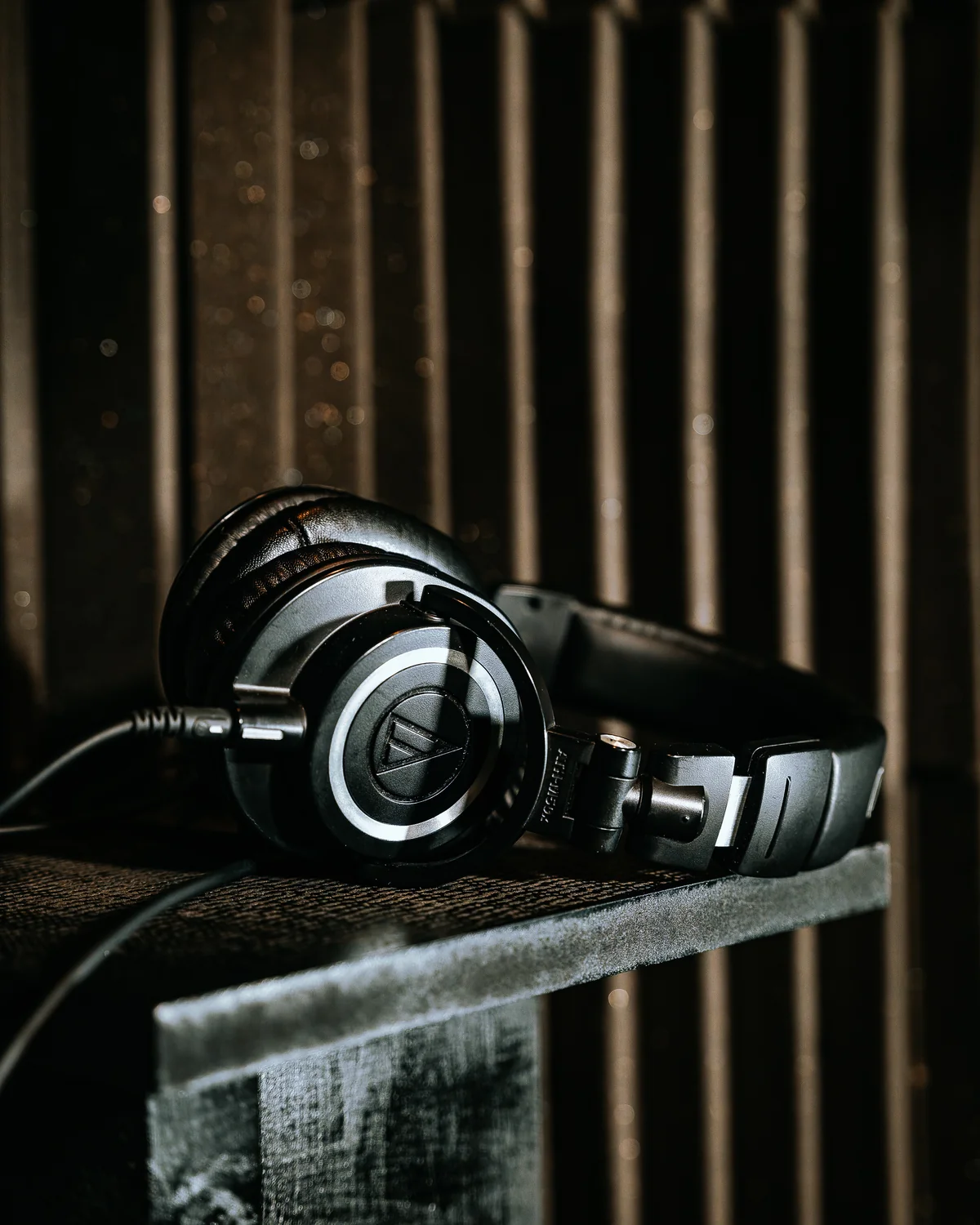 Studio headphones resting on a wooden crate against the live room’s wood-slat wall at Resonate